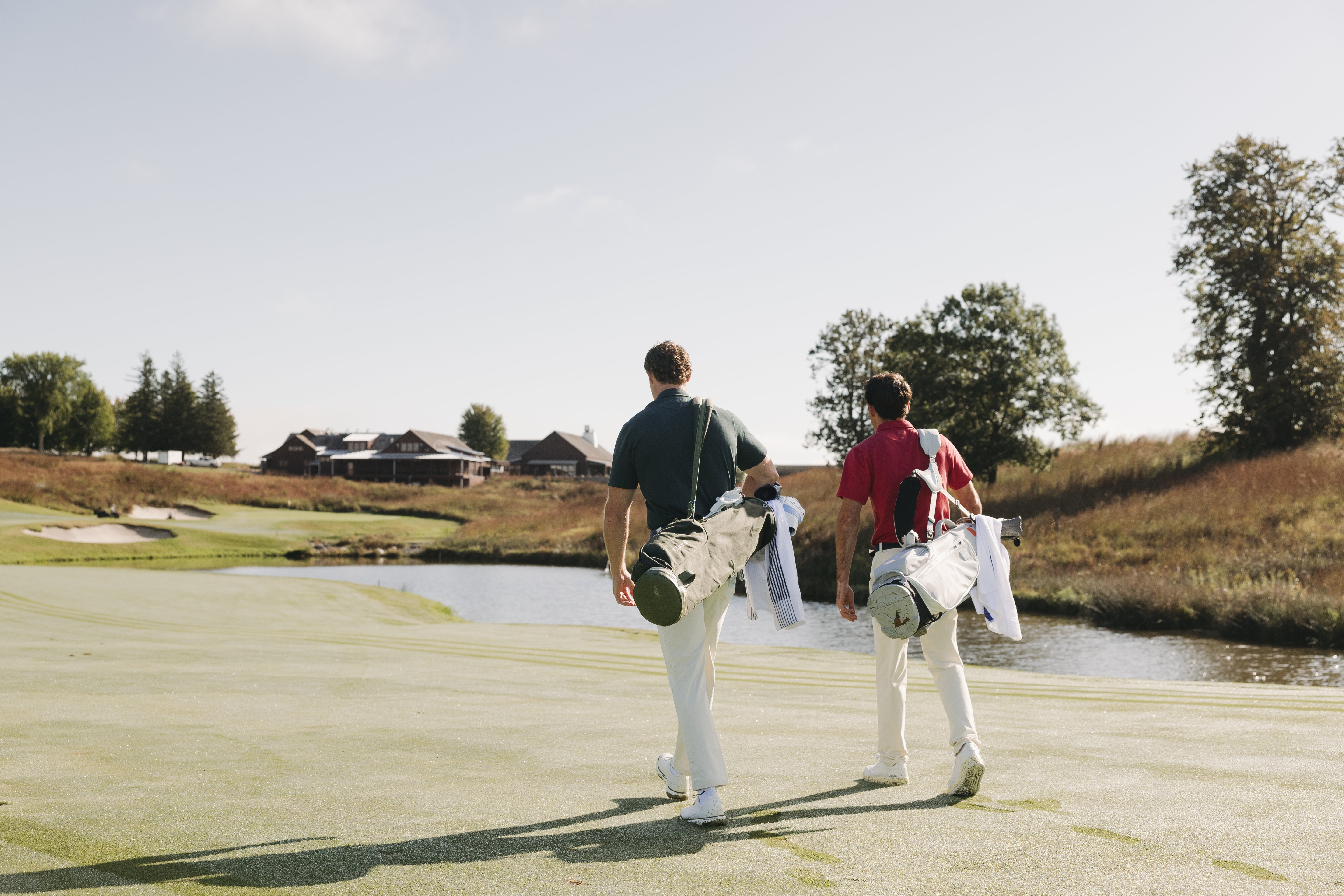 Two golfers walking on a golf course with a scenic background - Olydoe Golf
